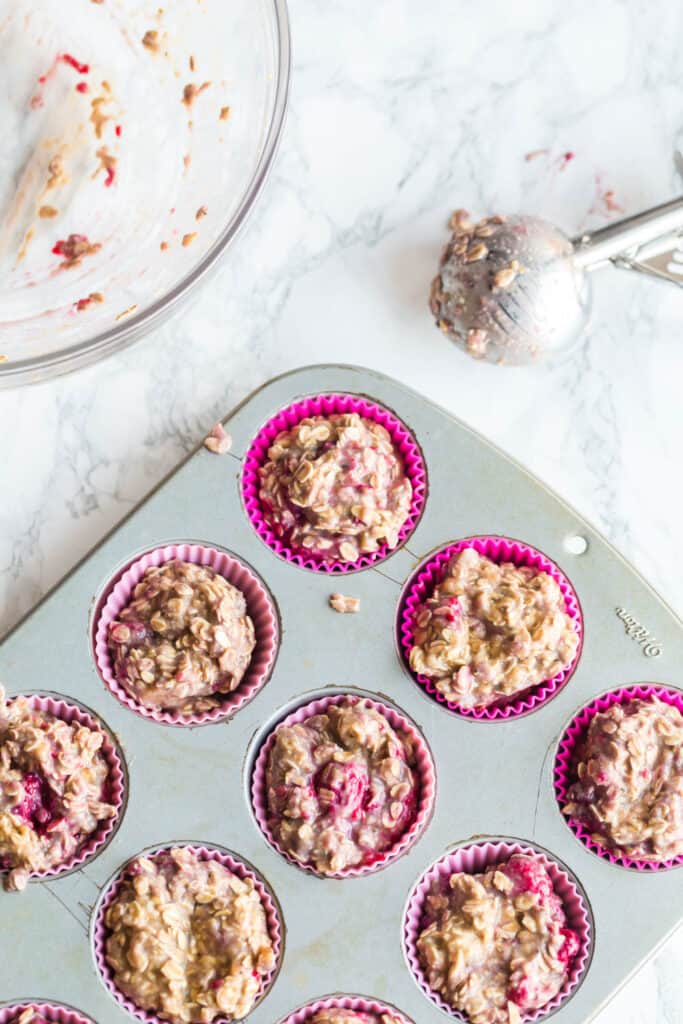 scooping muffin batter into a tin