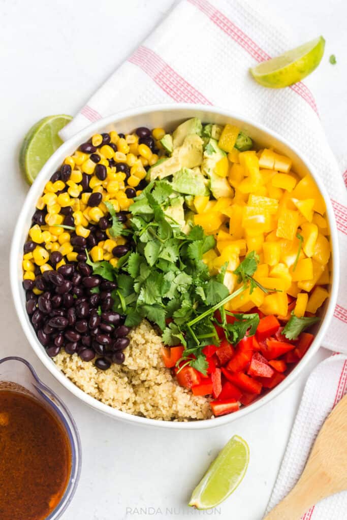 corn, black beans, cilantro, bell peppers, quinoa, avocado in a bowl for a summer salad