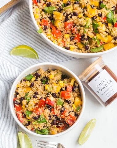 pretty spice jars next to clay bowls filled with a quinoa salad with limes