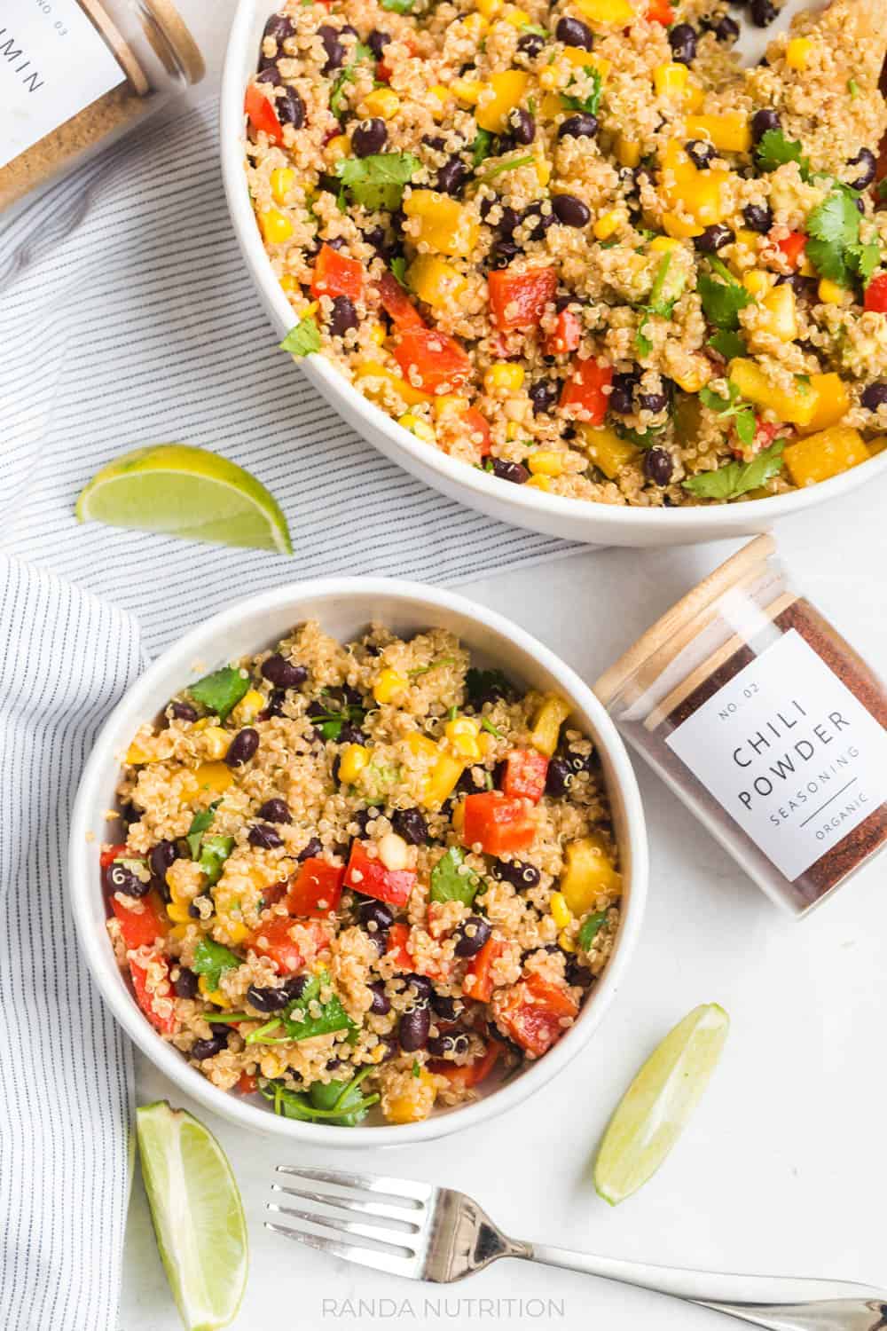 pretty spice jars next to clay bowls filled with a quinoa salad with limes