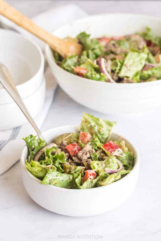 delicious burger salad in white bowls with a serving bowl in the background