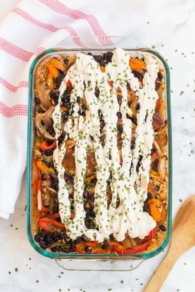 an overhead view of this cooked Chicken Fajita Bake Recipe in a glass casserole dish garnished with the homemade dairy-free cashew cream sauce