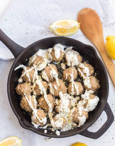 overhead shot of a cast iron skillet with cooked turkey meatballs with lemon and oregano