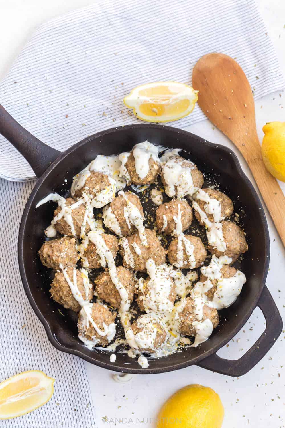 overhead shot of a cast iron skillet with cooked turkey meatballs with lemon and oregano
