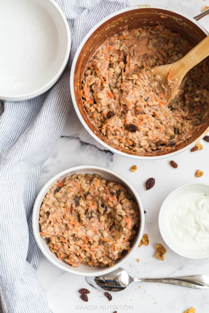 overhead view of healthy carrot cake oatmeal with raisins, greek yogurt, and carrots with cinnamon