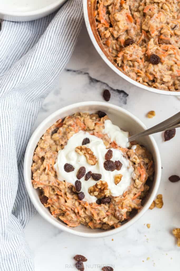 overhead view of healthy carrot cake oatmeal with raisins, greek yogurt, and carrots with cinnamon