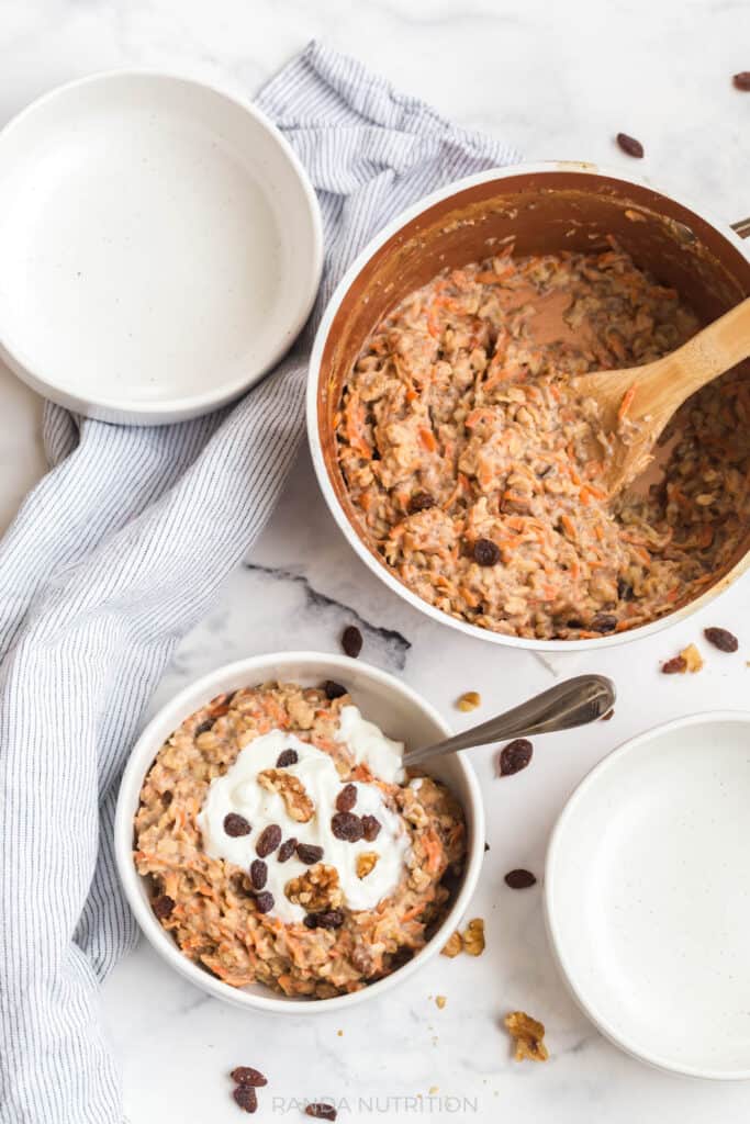 overhead view of healthy carrot cake oatmeal with raisins, greek yogurt, and carrots with cinnamon