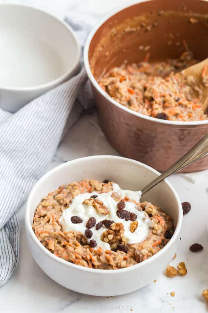 overhead view of healthy carrot cake oatmeal with raisins, greek yogurt, and carrots with cinnamon