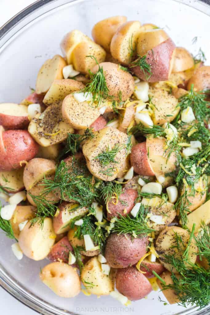 marinating potatoes with herbs and garlic before adding to a sheet pan