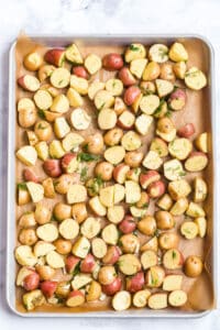 potatoes, garlic, dill weed, salt, pepper, and oil on a sheet pan