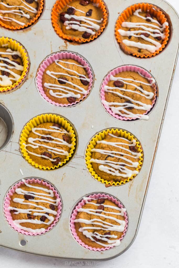 muffins with a cream cheese drizzle in a muffin tin