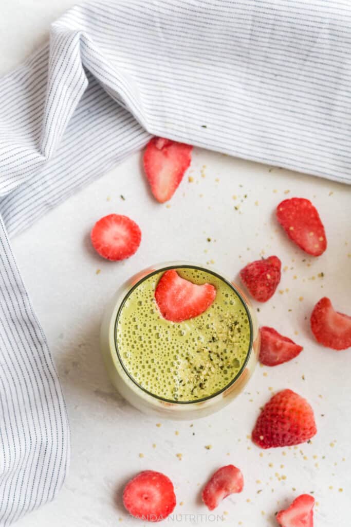 overhead view of green smoothie with strawberries