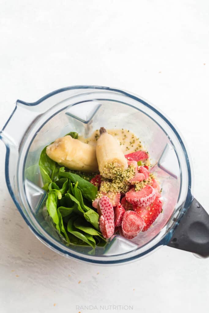 banana, spinach, strawberries, and greek yogurt in a vitamix