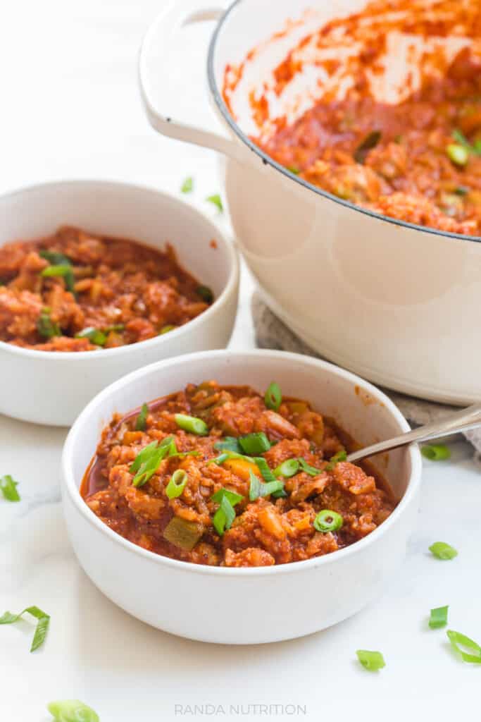 cajun chicken stew in a while bowl with green onions