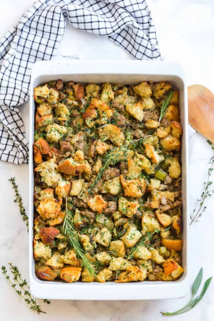 a top view of this easy sourdough bread dressing recipe with fresh herbs and spices in a white baking dish