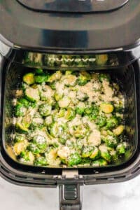 adding parmesan cheese over brussel sprouts in the air fryer