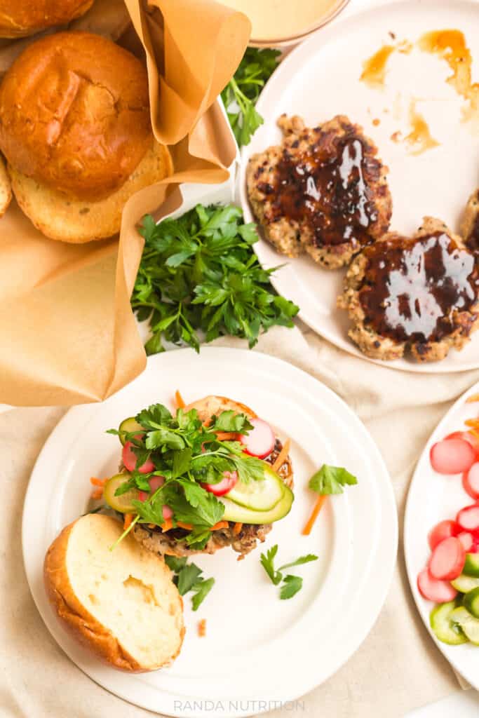 overhead shot of pickled vegetables over a burger topped with hoisin sauce