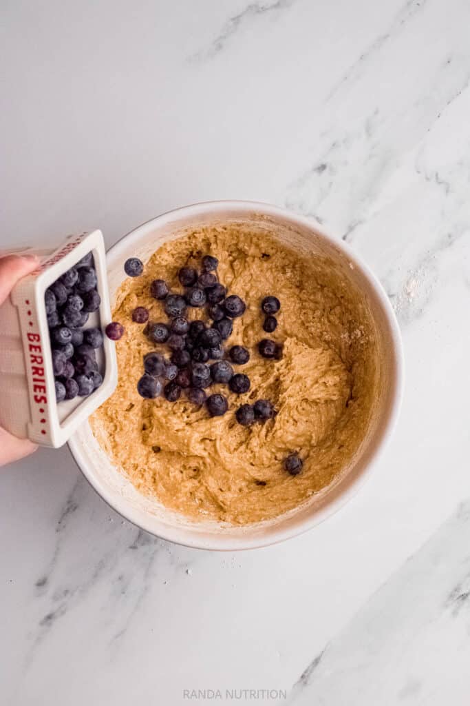 adding blueberries to a protein muffin batter