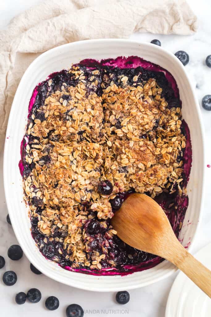 wooden spoon in a Sophie Conran dish surrounded by berry crisp