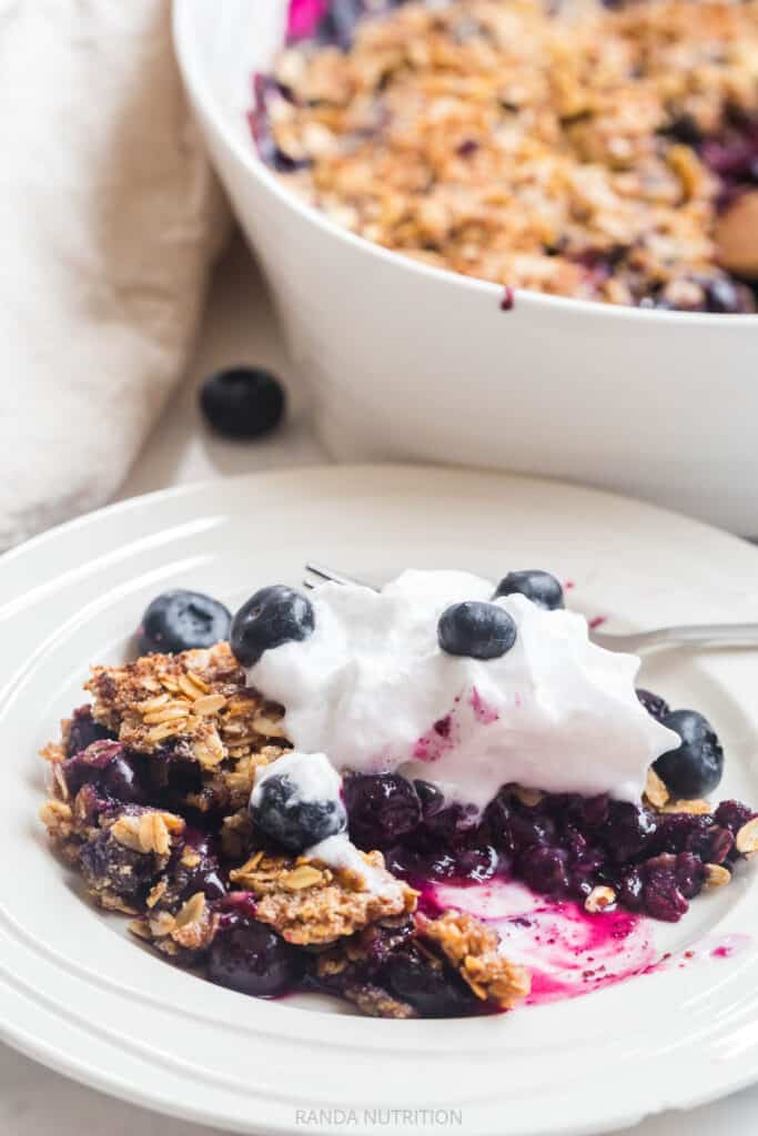 a slice of blueberry crisp topping with whipped cream and berries