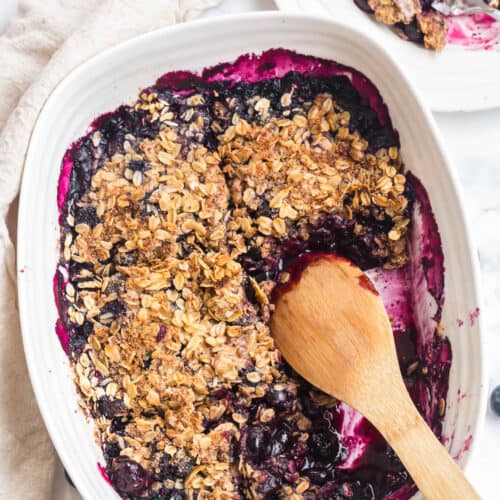 gluten free blueberry crisp with a wooden spoon