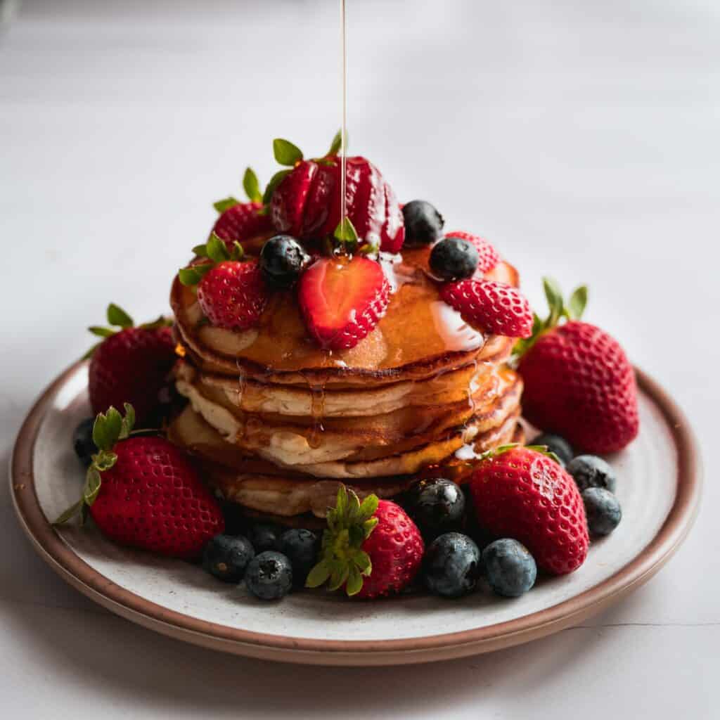 protein pancakes on a plate topped with maple syrup and strawberries