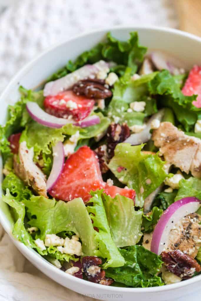 up close of strawberries, red onion, and feta cheese in a salad