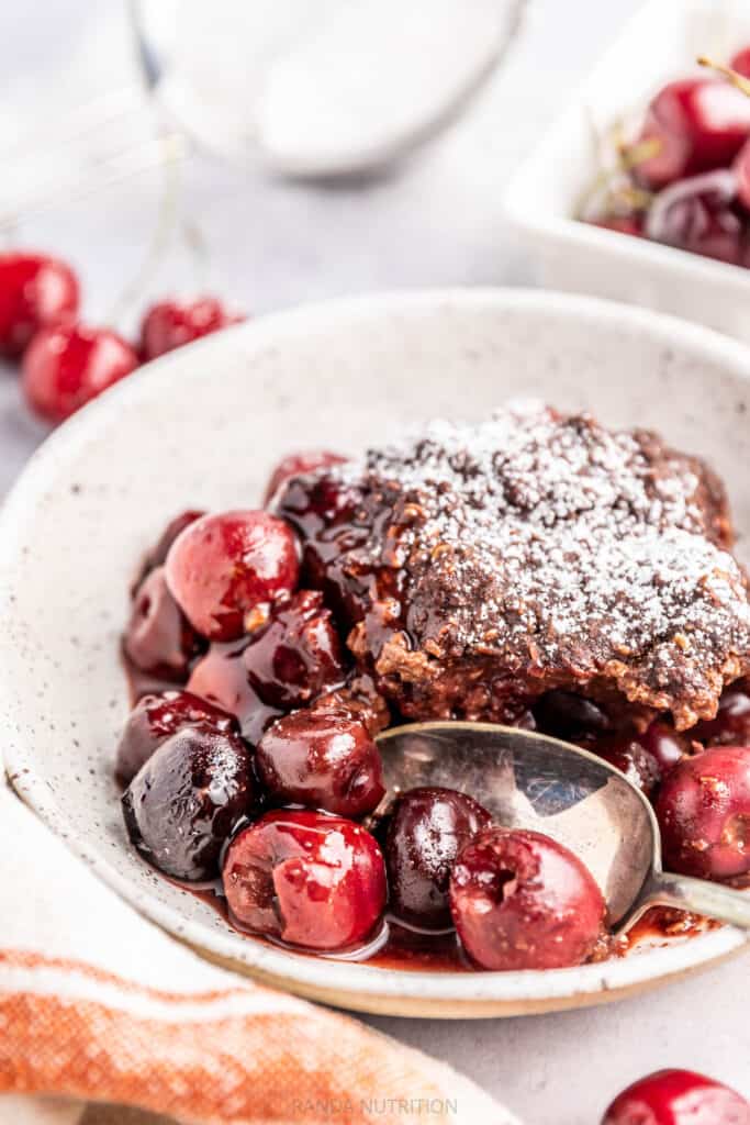 chocolate cherry cobbler served with a spoon with a powdered sugar topping