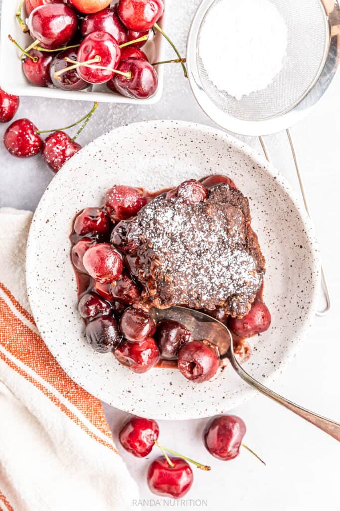 overhead shot of a chocolate cobbler in a bowl with cherries