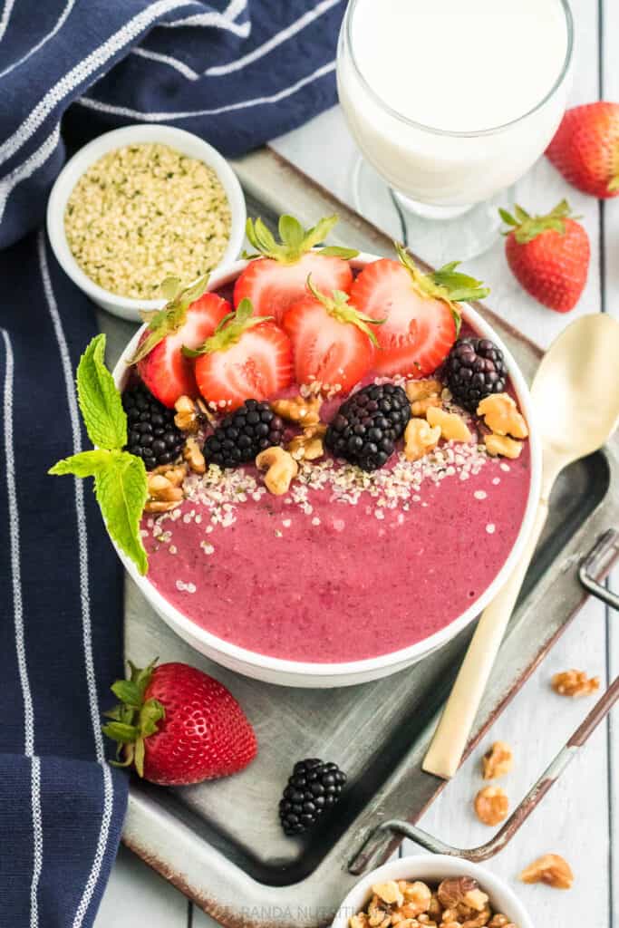 pink smoothie in a bowl with berries surrounding it