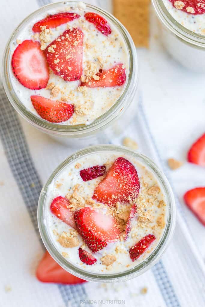 overhead look over strawberries and crushed graham crackers on top of a yogurt and oat meal prep breakfast