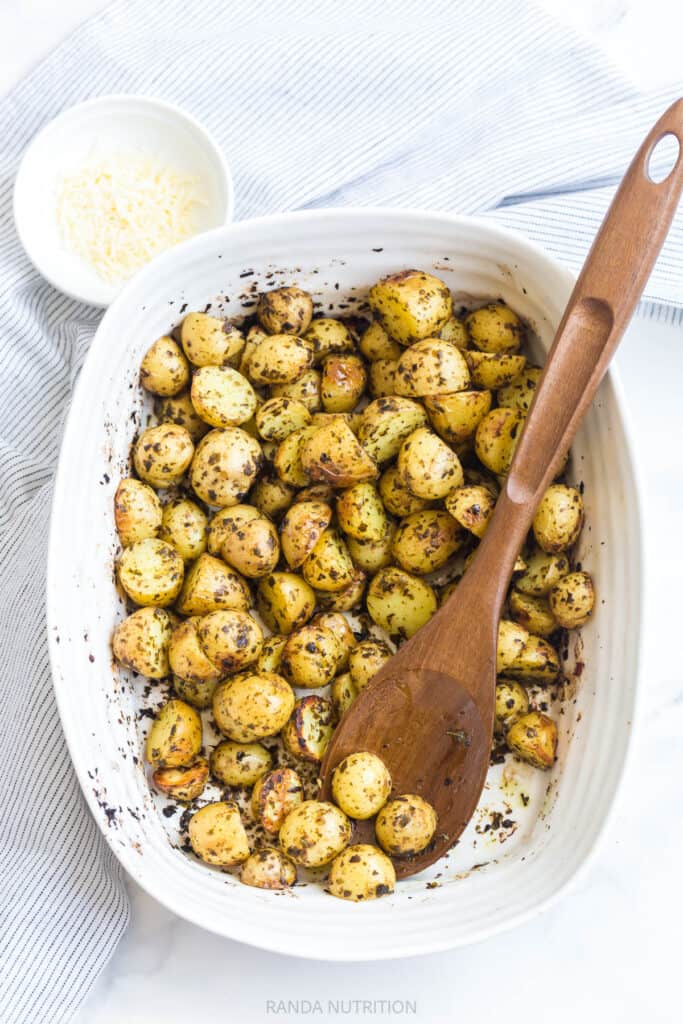 2 ingredient pesto potatoes in a white casserole dish with parmesan on the side