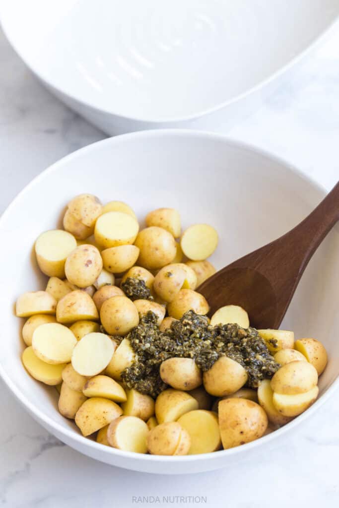 mixing pesto and potatoes together