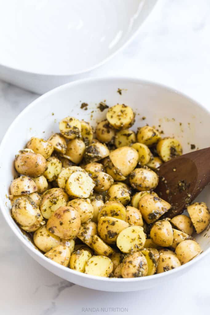 herbs with olive oil and garlic mixed with potatoes before going on a sheet pan