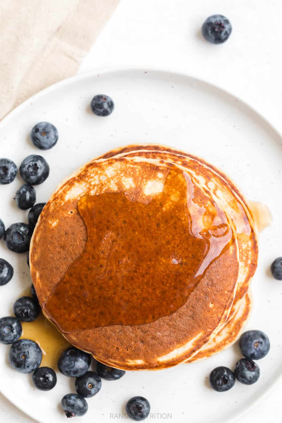 over top view of round pancakes topped with syrup and blueberries