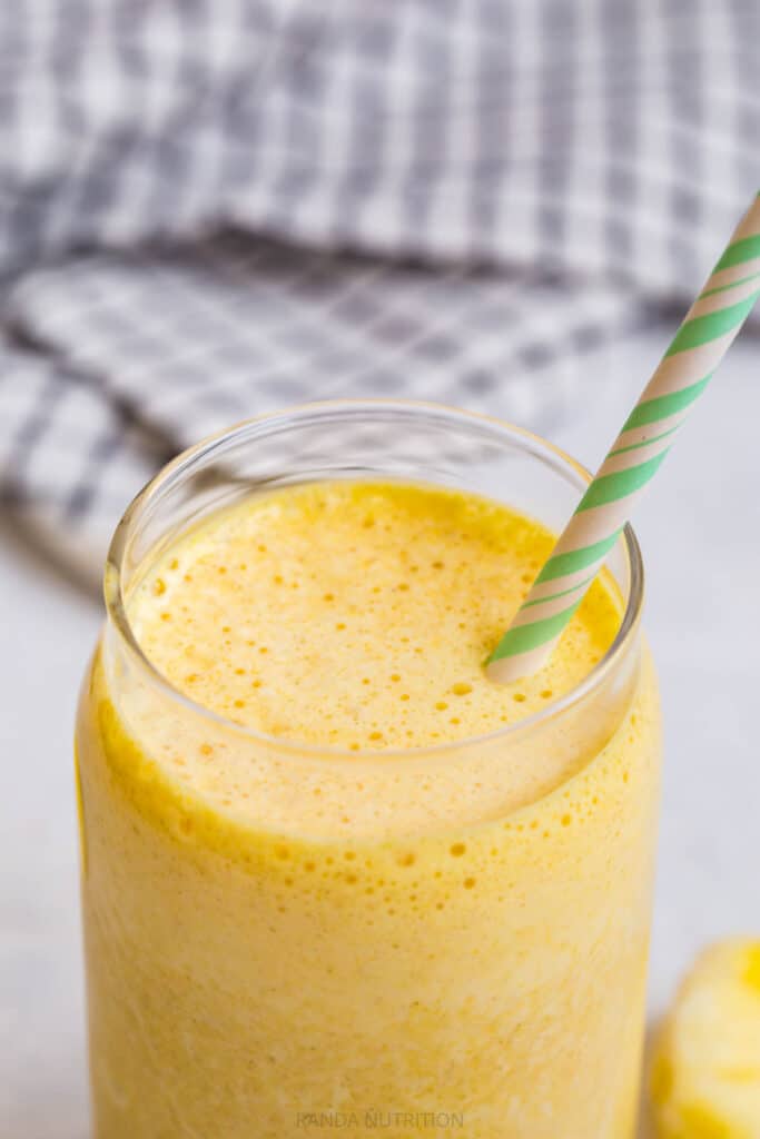 overhead view of yellow smoothie with a green paper straw