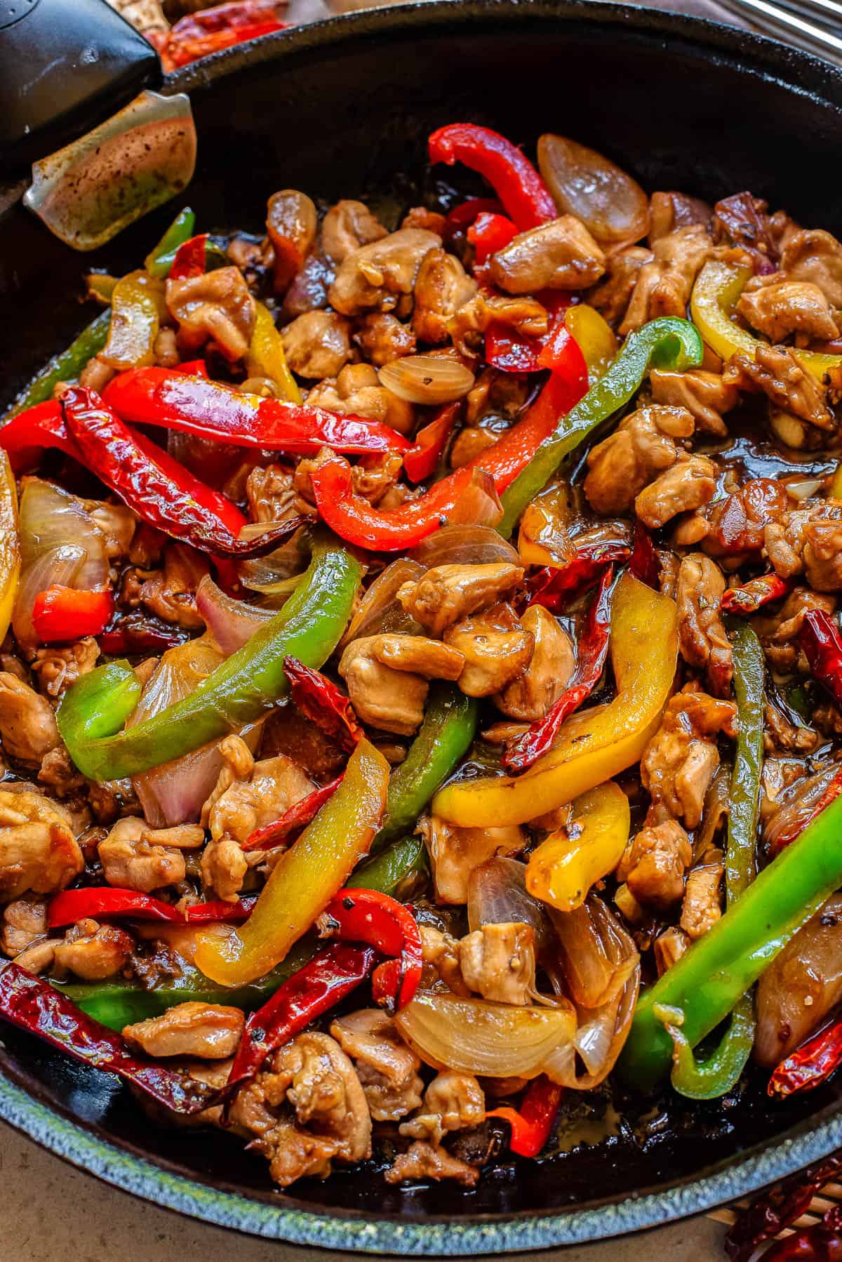 close of of cooked chicken thighs in a chinese black pepper sauce in a skillet