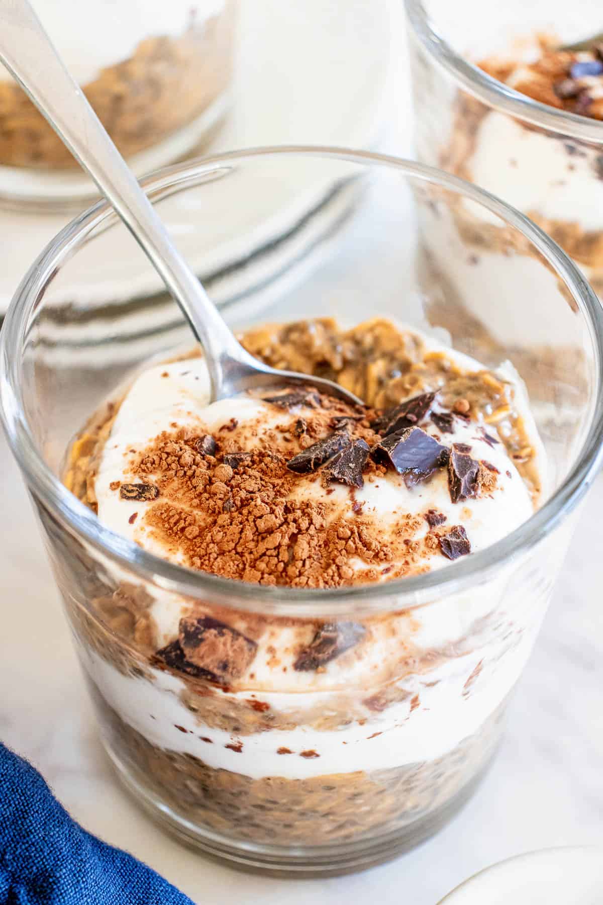 a spoon in a clear jar with oats and yogurt