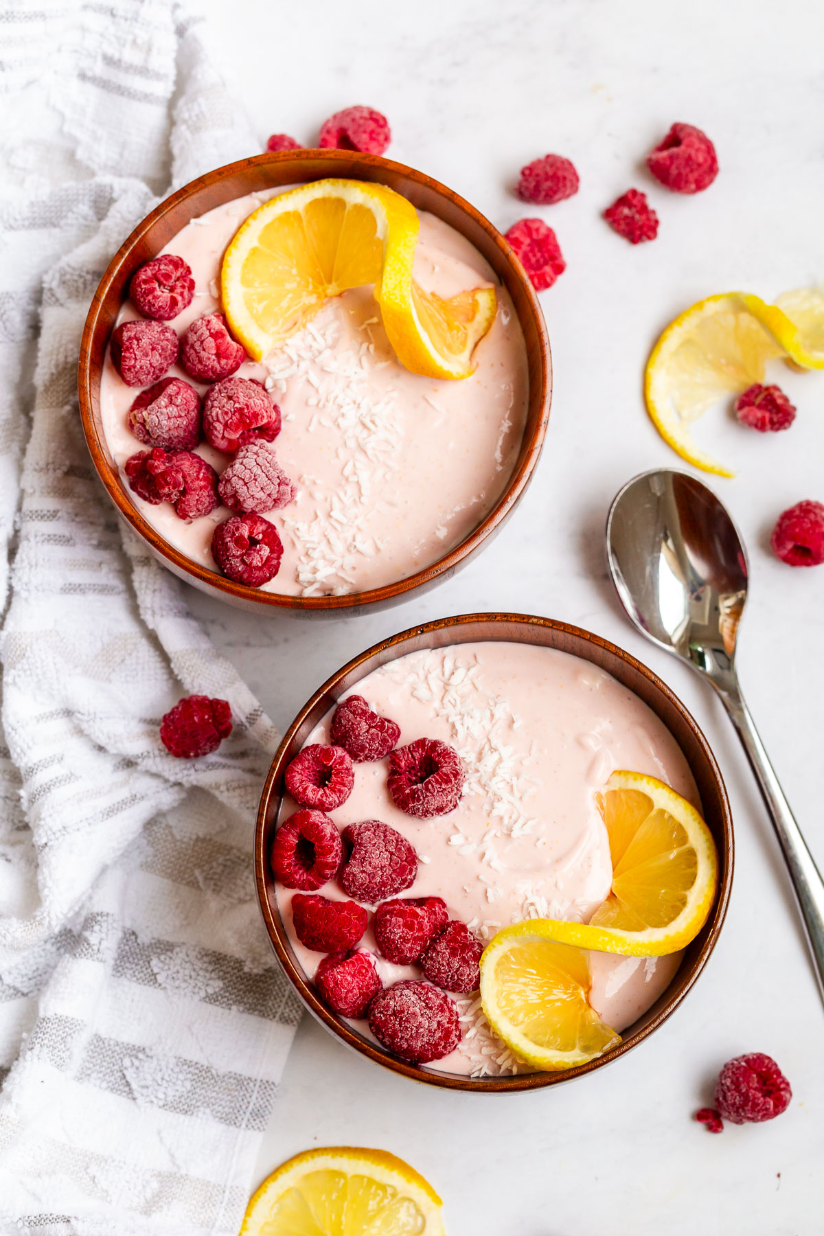 overhead shot of pink protein bowls topped with raspberries and lemons