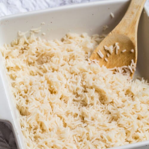 How to Cook Rice In The Oven (White, Brown, or Converted Rice) 9 Oven baked rice stirred and fluffed with a wooden spoon