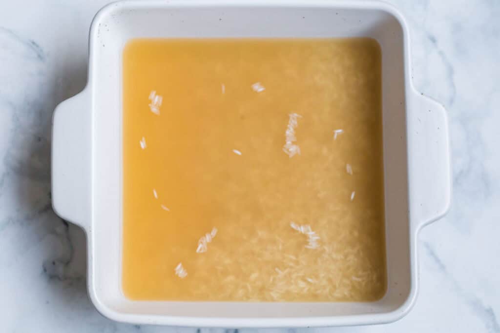 How to Cook Rice In The Oven (White, Brown, or Converted Rice) 4 Uncooked rice and broth in a baking dish before oven cooking