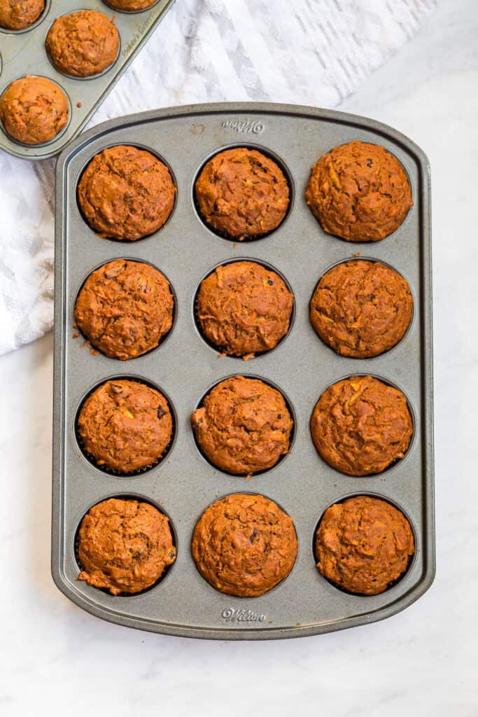 Gluten Free Morning Glory Muffins (Healthy & Moist) 7 Freshly baked gluten free morning glory muffins in a muffin pan, golden brown and ready to cool.